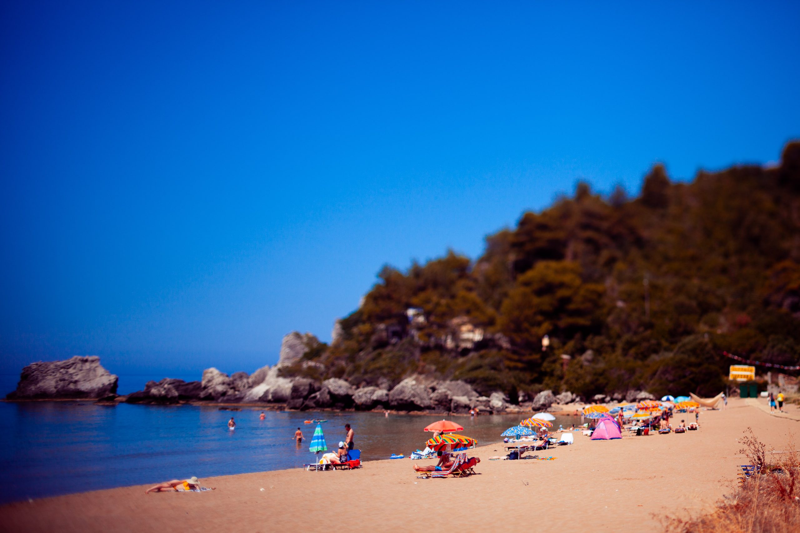 Corfu travel photography using a tilt-shift lens to create a miniature model effect of Glyfada Beach and Paralia Mirtiotissa.