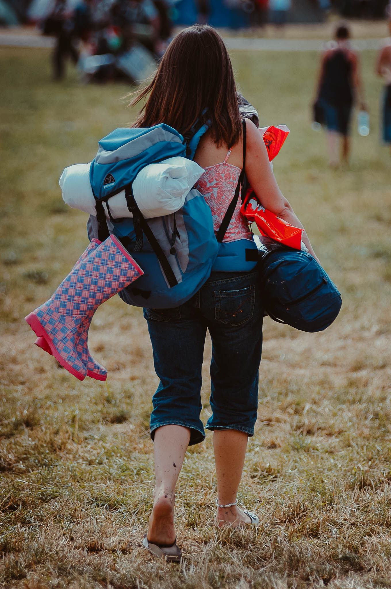 A festivalgoer arrives at Glastonbury Festival carrying the must-have Wellington boots